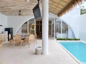 a patio with a table and chairs next to a swimming pool at Villa Sei Uluwatu by LODGELINK BALI in Uluwatu