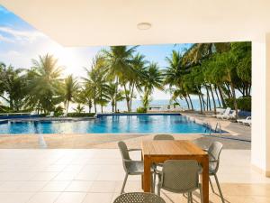a dining table and chairs in front of a swimming pool at Playa Azul Exclusive Suites in Tonsupa
