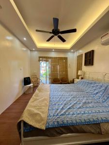 a bedroom with a bed with a ceiling fan at Villa Patria in Calatagan +5 photos