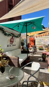 a patio with a table and a green umbrella at Jaguar Hostel in Viña del Mar