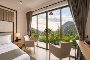 ein Schlafzimmer mit Bett, Stühlen und einem großen Fenster in der Unterkunft Onrock Boutique Hotel in Ella