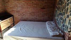 a bed in a room with a brick wall at Chalé Mandala de Pedra in São Thomé das Letras