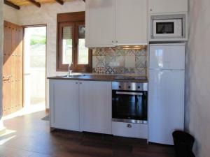 a white kitchen with a stove and a refrigerator at Beautiful villa with jacuzzi in Canillas de Albaida