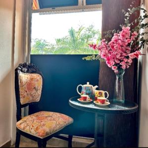 a small table with a vase of flowers and a table with a chair at Hotel Plaza Garibaldi in Caldas