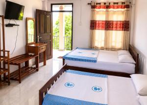 a room with two beds and a tv and a table at The Green View Guest House Haputale in Haputale