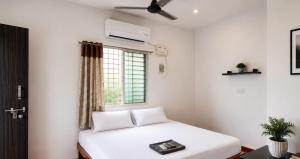 a bedroom with a white bed and a window at Nature Nest In in Auroville