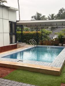 a large swimming pool in a yard with a building at Ginger Villa Farmstay, Thodupuzha in Idukki