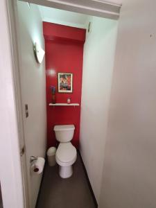 a bathroom with a white toilet in a red wall at Jaguar Hostel in Viña del Mar +19 photos