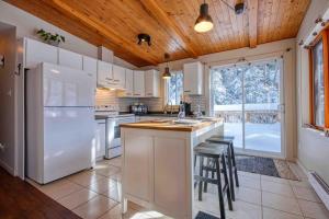 a kitchen with a white refrigerator and a counter with stools at Chalet familial, idéalement situé, billard-table-babyfoot-arcade in Saint-Faustin