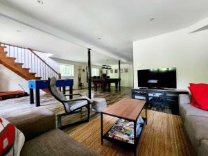 a living room with a couch and a flat screen tv at Chalet familial, idéalement situé, billard-table-babyfoot-arcade in Saint-Faustin