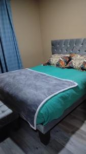 a bedroom with a bed with a green blanket on it at Habitaciones Express Calama in Calama