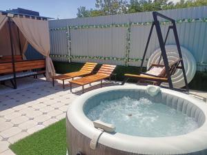 a hot tub with two chairs and a swing at Laguna Relax in Balqash
