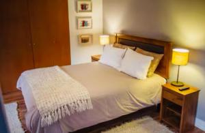a bedroom with a bed with two lamps on a night stand at Refugio en Camino a Farellones in Lo Barnechea