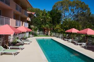 a pool at a hotel with chairs and umbrellas at The Roy in Rainbow Beach