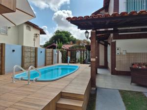 a pool in a backyard with a wooden deck and a house at Casa em Salinas in Salinópolis