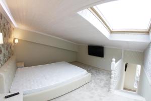 um quarto com uma cama branca e uma clarabóia em Apartments on Yuzhnykh Kultur em Adler