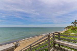 an empty beach with a wooden fence and the ocean at Hydrangea Lane Beach Cottage in Mashpee
