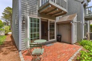 a patio with a table and chairs and a balcony at Hydrangea Lane Beach Cottage in Mashpee