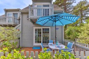 a table with a blue umbrella in front of a house at Hydrangea Lane Beach Cottage in Mashpee