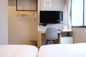 a bedroom with two beds and a tv and a chair at Luma Urban Hotel 高田馬場 in Tokyo