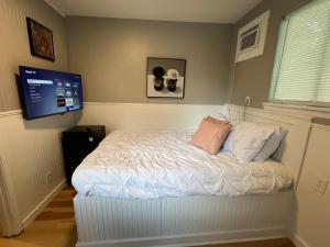 a bedroom with a white bed with a flat screen tv at Berlins Cozy Apartment Pets Welcome in North Little Rock