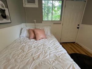 a white bed with pink pillows in a bedroom at Berlins Cozy Apartment Pets Welcome in North Little Rock