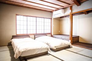 two beds in a room with a large window at 白灯-Hakuto- Muikamachi in Minami Uonuma