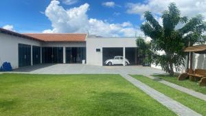a white house with a car in the garage at Lar com piscina in Primavera do Leste
