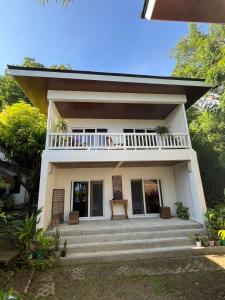 a small white house with a balcony and stairs at Villa Patria in Calatagan