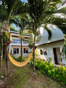 a hammock in front of a house with palm trees at Villa Patria in Calatagan