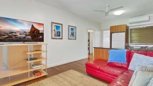 a living room with a red couch and a kitchen at Picnic Bay Apt 3. in Picnic Bay +14 photos