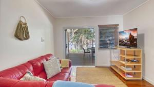 a living room with a red couch and a table at Picnic Bay Apt 3. in Picnic Bay