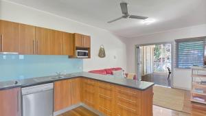 a kitchen with wooden cabinets and a living room at Picnic Bay Apt 3. in Picnic Bay