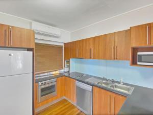 a kitchen with wooden cabinets and stainless steel appliances at Picnic Bay Apt 3. in Picnic Bay