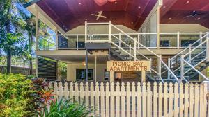 a house with a fence with a sign in front of it at Picnic Bay Apt 3. in Picnic Bay