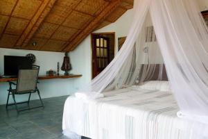 a bedroom with a bed with a mosquito net at Oceanside Villa in Puerto Galera
