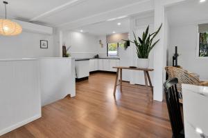 a kitchen with white cabinets and a wooden floor at Birdwing Retreat in Picnic Bay