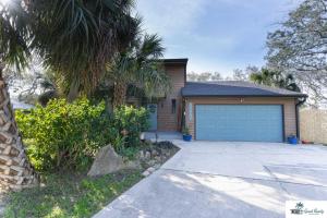 a house with a garage and a palm tree at Waterfront Zen-Dock, Paddleboards, Jacuzzi & Games in St. Augustine