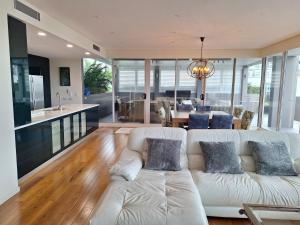 a living room with a white couch and a kitchen at Honeysuckle Executive Apartments in Newcastle