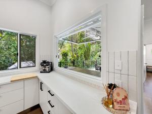 a kitchen with white cabinets and a large window at Tropic 21 in Picnic Bay