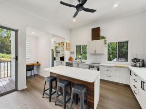 a kitchen with white cabinets and a table and stools at Tropic 21 in Picnic Bay