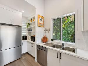 a kitchen with white cabinets and a sink and a window at Tropic 21 in Picnic Bay