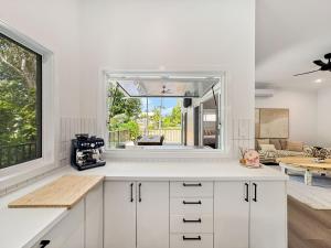 a kitchen with white cabinets and a large window at Tropic 21 in Picnic Bay