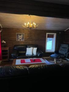 a living room with a black leather couch and a chandelier at Øse Camping in Gratangen