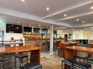 a bar with wooden tables and stools in a restaurant at Queens Head Hotel in West Hobart