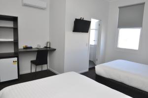a bedroom with two beds and a desk with a chair at Queens Head Hotel in West Hobart