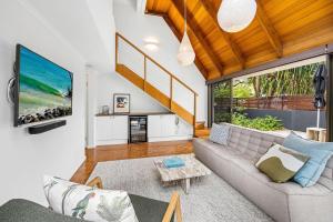 a living room with a couch and a tv at Salt Luxury Location in Sunshine Beach