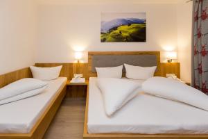 2 Betten in einem Zimmer mit weißer Bettwäsche und Kissen in der Unterkunft Ferienhaus Alpenherz in Finkenberg