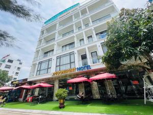 a hotel with red umbrellas in front of it at Khách Sạn Moonlight FLC Sầm Sơn in Sầm Sơn