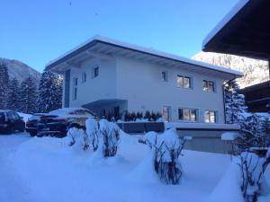 ein schneebedecktes Haus mit einem davor geparkt in der Unterkunft Ferienhaus Alpenherz in Finkenberg